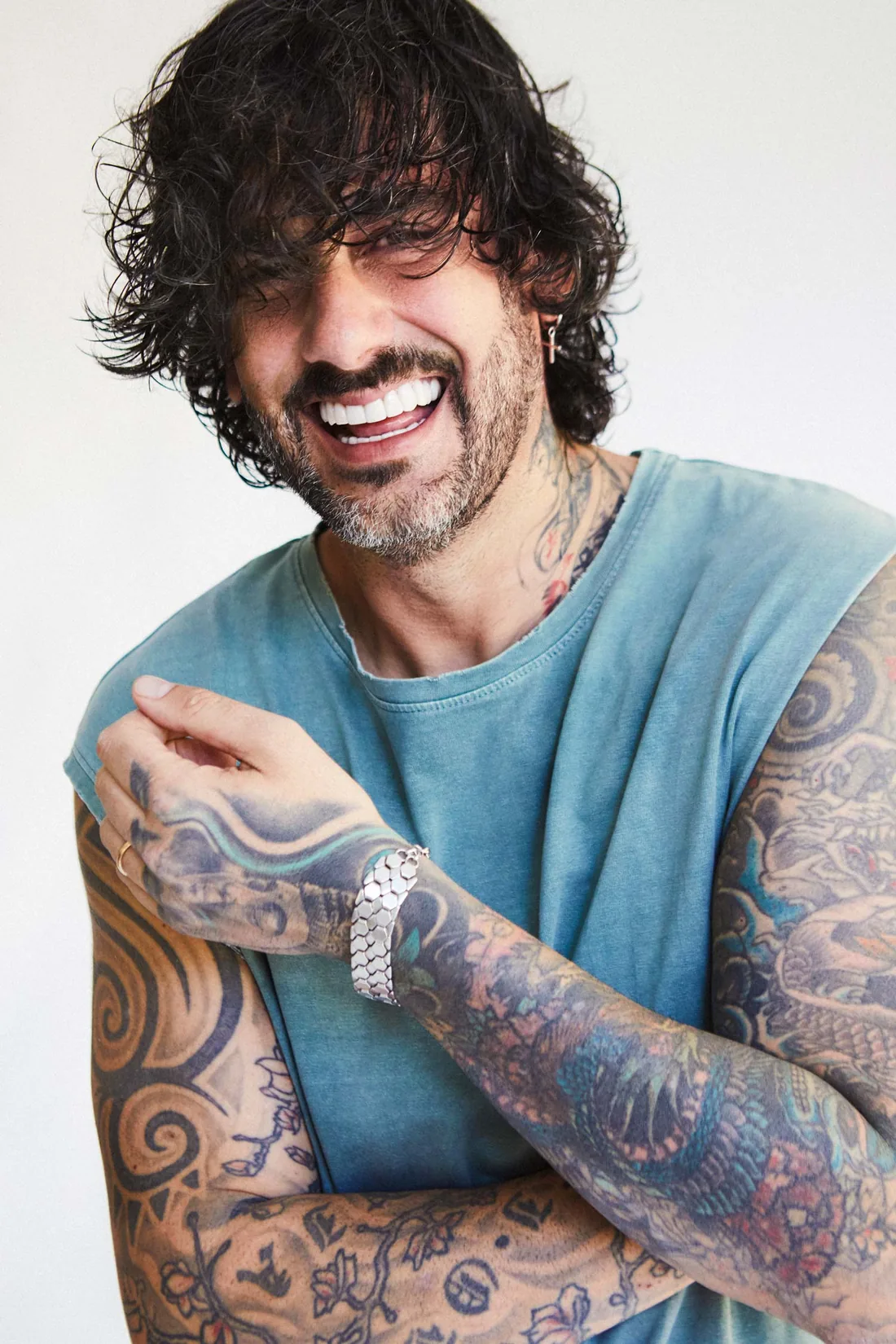 Melen en 2026, riéndose, con camiseta azul y los brazos tatuados